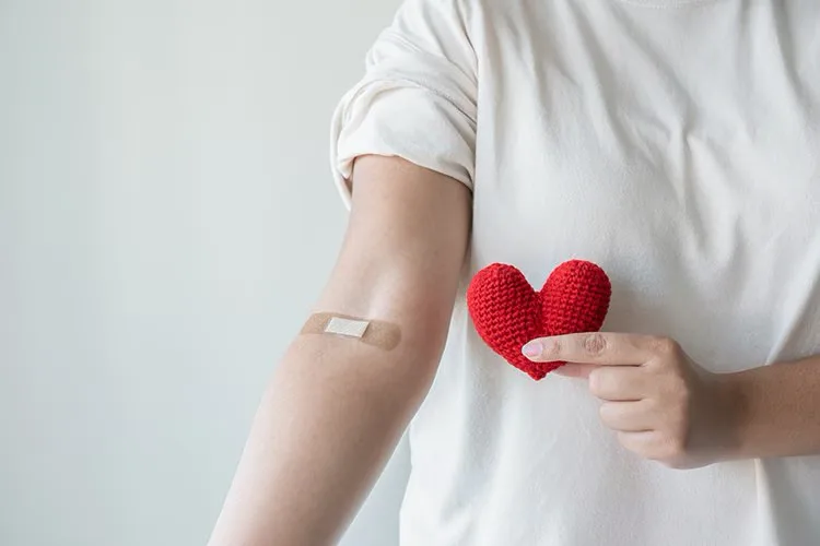 Blood donor holding a red heart after donating